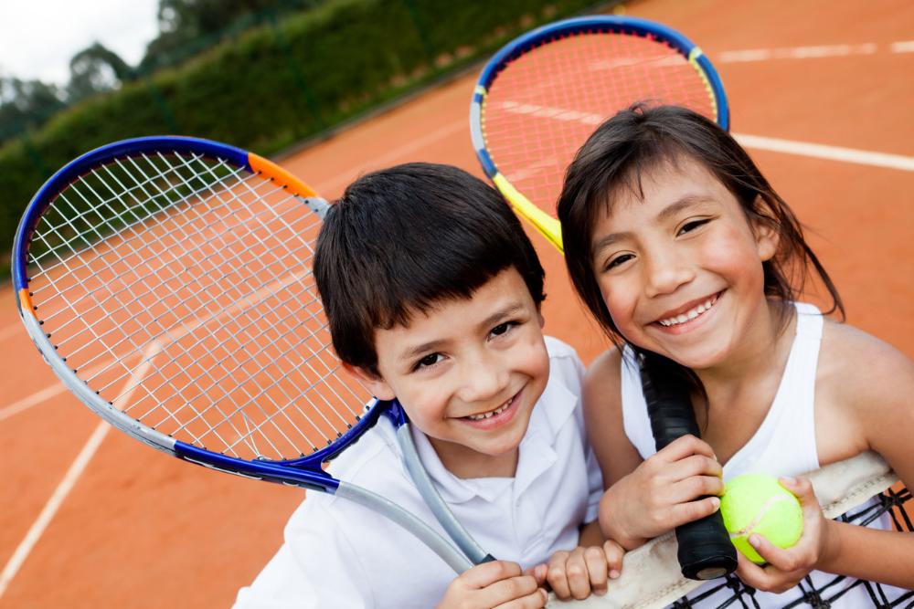 young girl and boy smiling on a tennis court