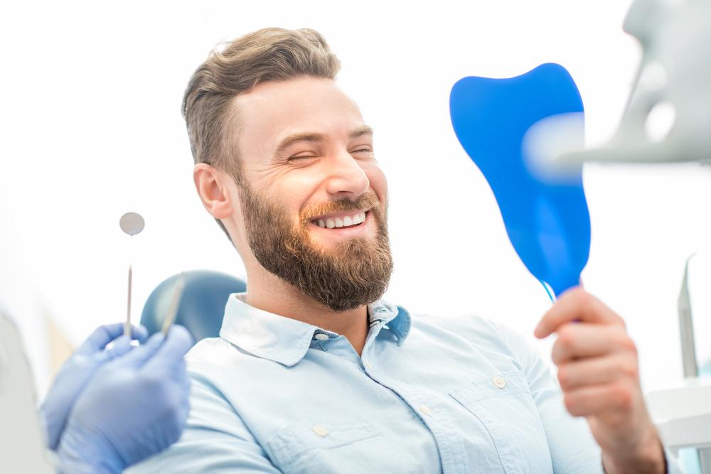 man smiling in mirror after dental cleaning in north york