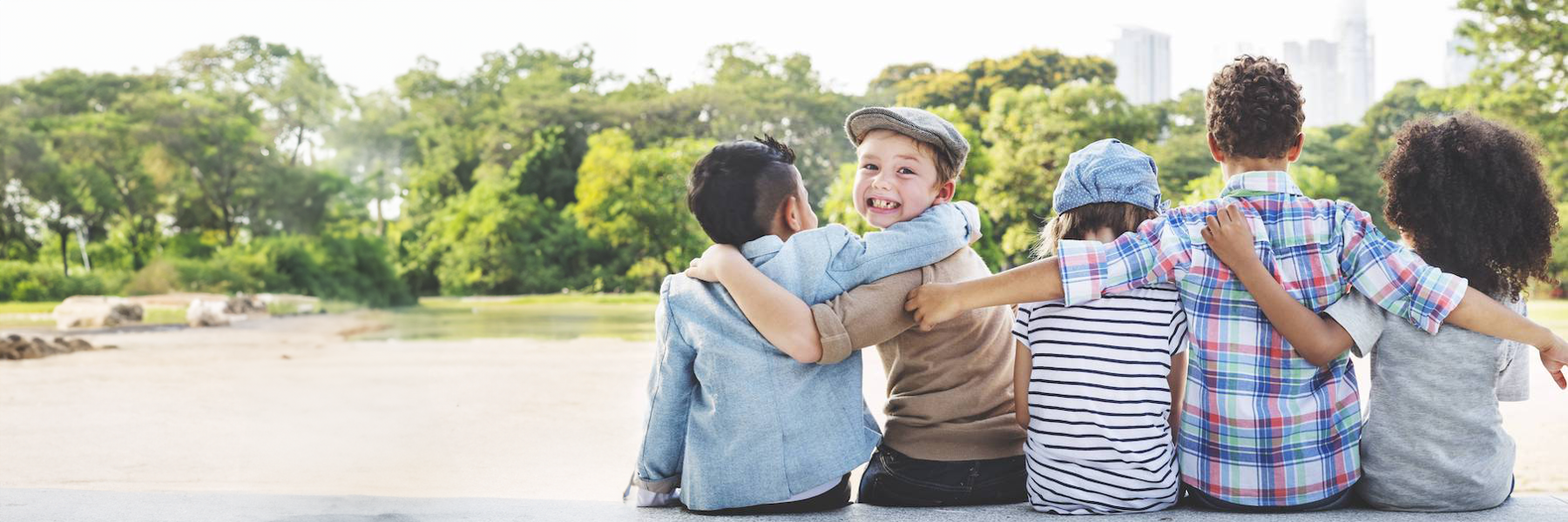 young boy turning to camera while hugging friends