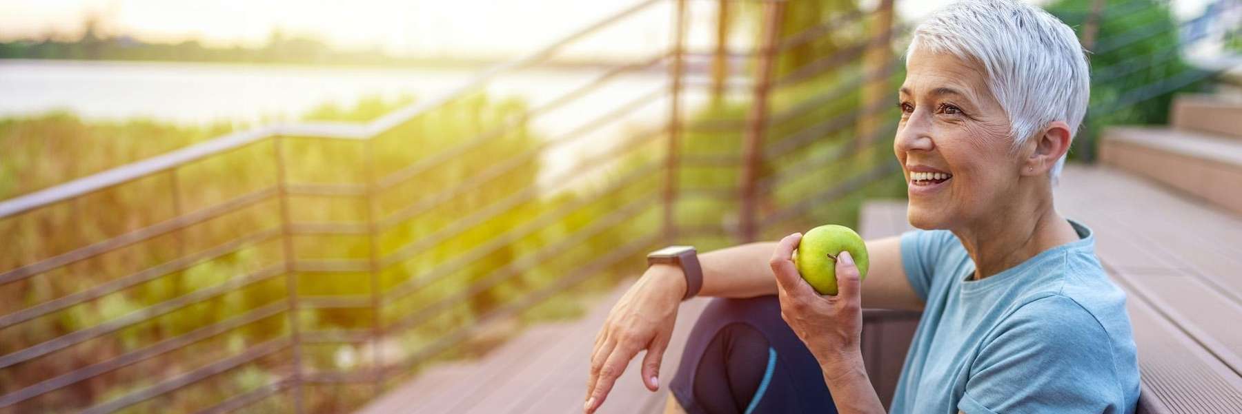 woman eating an apple while sitting on the porch 