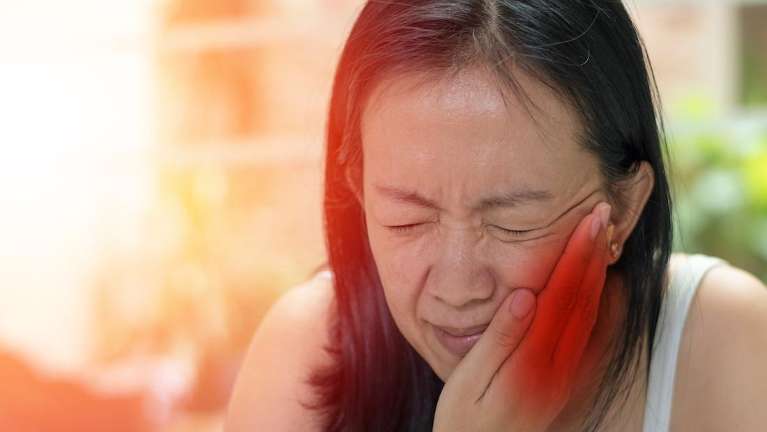 woman holding jaw from TMJ pain