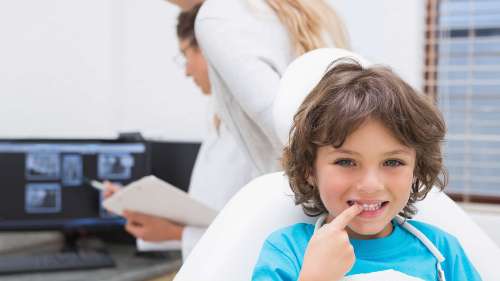 young boy pointing smiling in dental chair