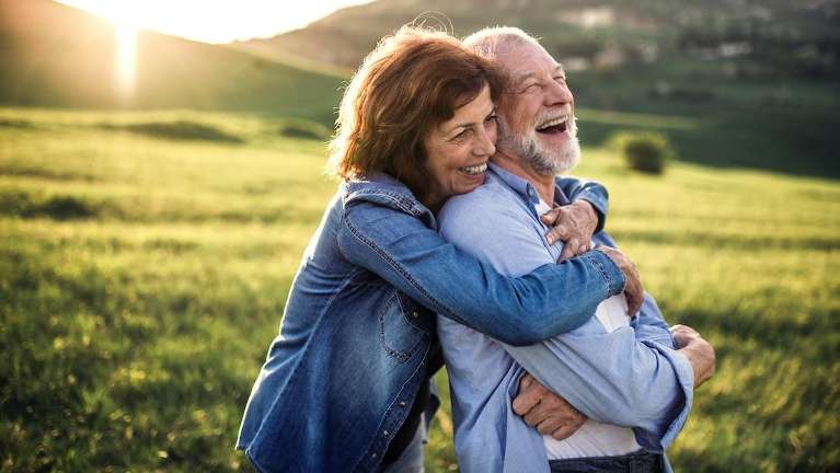 man being hugged from behind by his wife