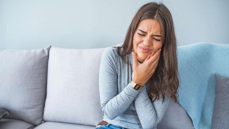 woman holding jaw in pain from infected tooth
