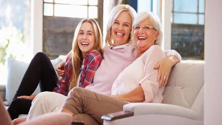 Mother, daughter, and grandmother laughing on the couch in a north york home