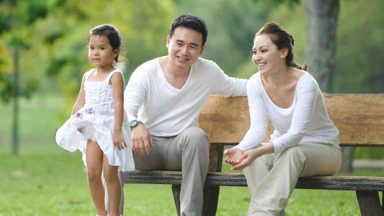Mo, dad, and daughter sitting on park bench in north york
